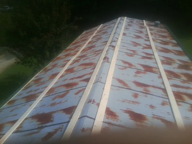 Rusted metal roof panels with new wood purlins before replacement — Storm Damage Roof Repair in Yoder by Roofing Brothers