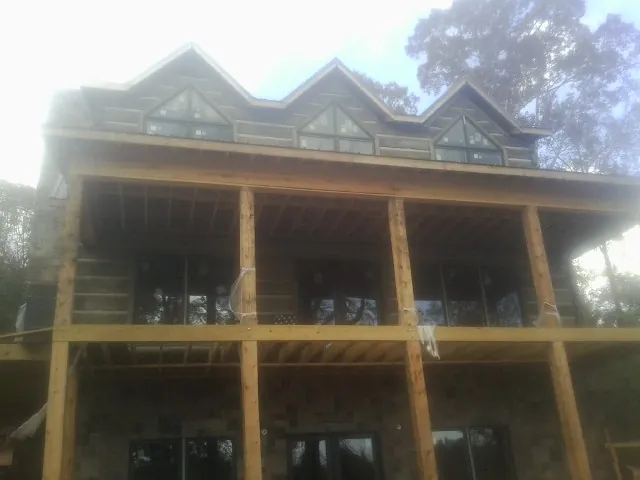 Dormers and porch framing on a large log home under construction — Roof Coating work by our crew in Yoder